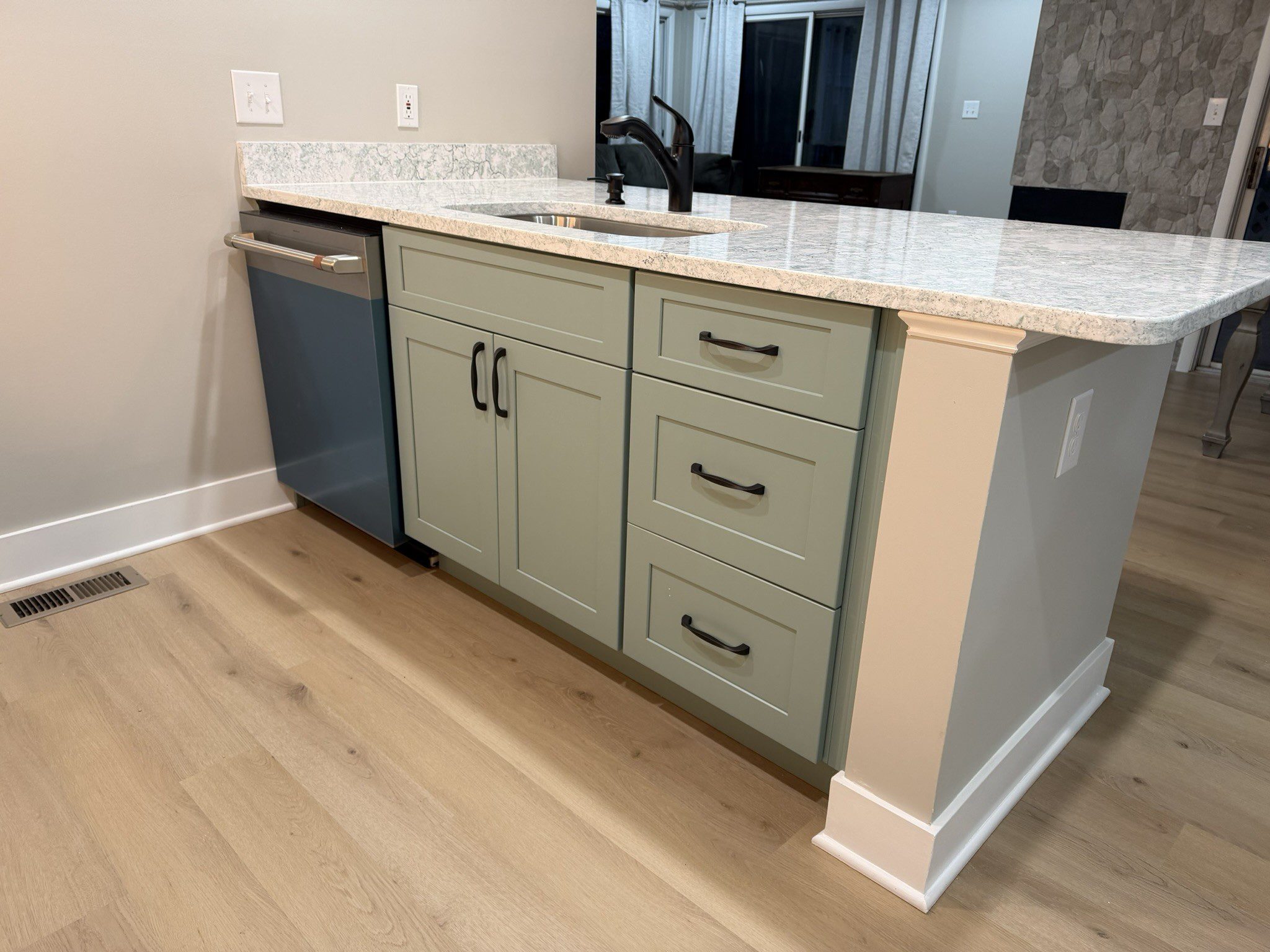 Granite-topped kitchen island with sage cabinets